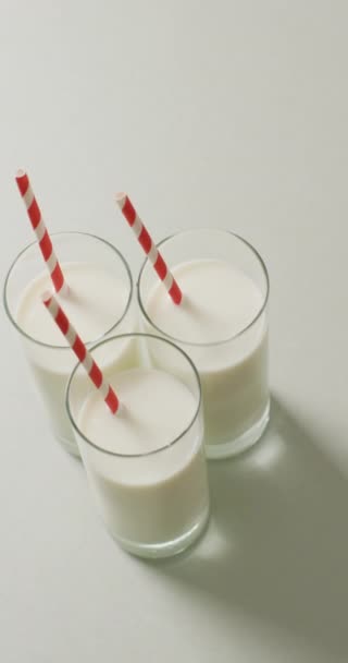 三杯牛奶与红色和白色稻草灰色背景的垂直视频 鲜奶及奶类饮品 — 图库视频影像