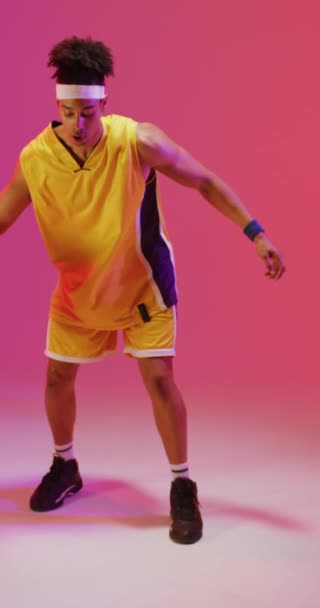 Vertical Video Biracial Male Basketball Player Bouncing Ball Pink Background — Stock Video