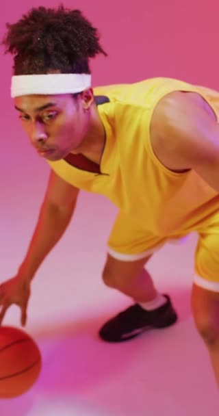 Vertical Video Biracial Male Basketball Player Bouncing Ball Pink Background — Stock Video