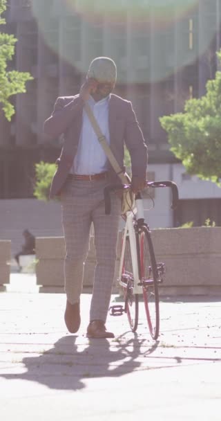 在城市里非洲裔美国人在阳光下骑自行车用智能手机聊天的垂直视频 身体的包容性 数字游牧民族在城市里四处游荡 — 图库视频影像