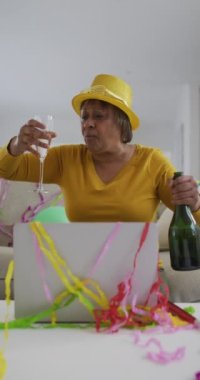 Üst düzey Afro-Amerikan kadının şampanya ile kutlama videosu dizüstü bilgisayar araması yapıyor. yaşlılar yaşam tarzı, kutlama ve iletişim teknolojisi.