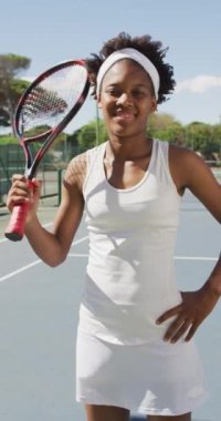 Mutlu Afro-Amerikan bayan tenis oyuncusunun tenis raketi ile portresinin dikey videosu. kadın tenis, spor ve yarışma.