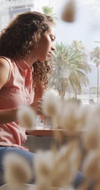 Kafede kahve içen Afro-Amerikan kadının dikey videosu. dijital göçebe hareket halinde.