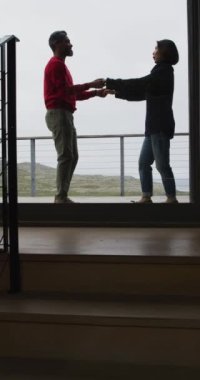 Evde dans eden ve el ele tutuşan mutlu çiftin dikey videosu. Evde kaliteli zaman geçirmek.