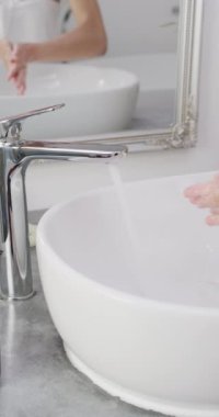 Banyoda ellerini yıkayan melez bir kadının dikey videosu. Güzellik, sağlık ve kadın spa konsepti.
