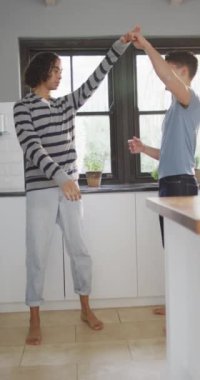 Mutfakta dans eden mutlu çiftin dikey videosu. Evde kaliteli zaman geçirmek.