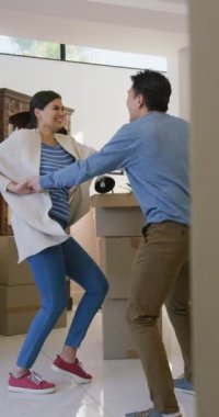 Yeni evde dans eden mutlu Asyalı çiftin dikey videosu. Yaşam tarzı, taşınma ve yeni ev konsepti