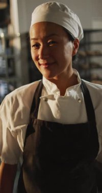 Pastanedeki mutlu Asyalı kadın fırıncının dikey portresi. küresel iş ve fırın.