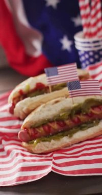 Amerikan bayraklı sosisli sandviçlerin dikey videosu ve çubuklu bardaklar. yemek, aşçılık, yemek ve beslenme konsepti.