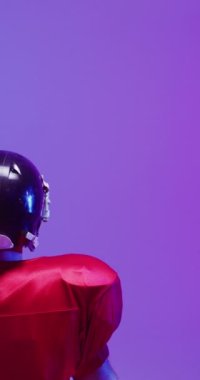 Kafkasyalı erkek Amerikan futbolcunun topu tuttuğu dikey video, neon ışıklı. Spor, hareket, eğitim ve aktif yaşam tarzı kavramı.