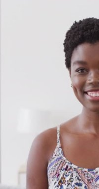 Vertical video half portrait of african american woman smiling to camera indoors with copy space. Health, happiness, inclusivity and lifestyle concept.