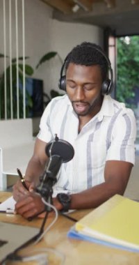 Mutfaktaki masada oturup video bloğu yapan mutlu Afro-Amerikan bir adamın dikey videosu. Evde yalnız zaman geçirmek..