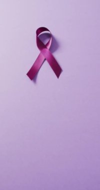 Mor arka planda mor kurdelenin dikey videosu. Sağlık, önleme, ilaç, semboller ve kanser farkındalığı kavramı.