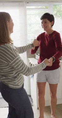 Evde dans eden mutlu beyaz lezbiyen çiftin dikey videosu. Evde birlikte vakit geçirmek..