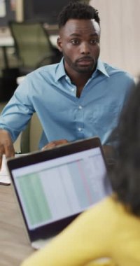 Ofisinde dizüstü bilgisayarı olan mutlu kadın ve erkeğin dikey videosu. İş adamları ve ofis kavramında çalışmak.