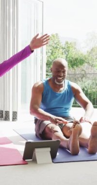 Farklı yaştaki mutlu çiftin evde birlikte yoga egzersizi yaptığı dikey video. Mutluluk, sağlık, emeklilik, birliktelik, ev hayatı ve kapsayıcılık kavramı.