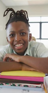 Sınıfında not defterleri olan mutlu Afrikalı Amerikalı bir öğrencinin dikey portresi. okul ve eğitim.