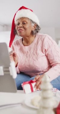 Mutlu son sınıf Afro-Amerikan kadınlarının Noel 'de tablet kullanarak video görüşmesi yaptığı dikey bir video. Emeklilik, evde vakit geçirme ve Noel konsepti.