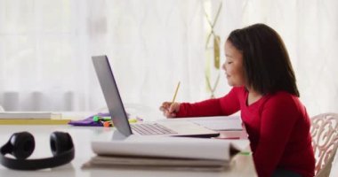 Mutlu Asyalı kızın online ders aldığı bir video. Çocukluk, e-öğrenim, evde eğitim ve online eğitim kavramı.