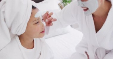 Mutlu Asyalı anne ve kızının yüzlerini nemlendirip eğlendiği bir video. Aile, annelik, ilişkiler ve birlikte kaliteli zaman geçirme konsepti dijital olarak oluşturulmuş video.