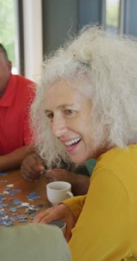 Bulmacalı mutlu yaşlı kadın ve erkek arkadaşlarının dikey videosu. aktif emeklilik yaşam tarzı ve kıdemli ilişki.