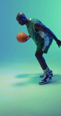 Yeşil arka planda zıplayan Afrikalı Amerikalı erkek basketbolcunun dikey videosu. Spor ve rekabet konsepti.