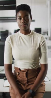 Ofisteki gülümseyen Afrikalı Amerikalı iş kadınının dikey video portresi. Yaratıcı bir iş yerindeki bedensel kapsayıcılık.