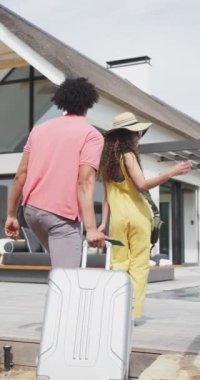 Yaz tatilinde bavullarıyla gelen mutlu çiftin dikey videosu. Tatil, seyahat, birliktelik, mutluluk ve kapsayıcılık kavramı.