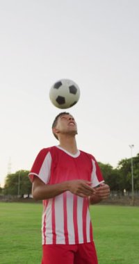 Saha tekmesindeki çift ırklı futbolcunun dikey videosu. Erkek futbol takımı, kapsayıcılık ve takım sporlarına uygunluk.