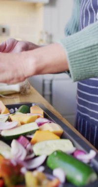 Mutfakta durup yemek hazırlayan yaşlı beyaz bir kadının dikey videosu. Evde yalnız zaman geçirmek..