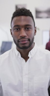 İşteki gülümseyen Afrikalı Amerikalı adamın dikey videosu. Yaratıcı bir işte, iş yerinde bedensel bütünlük.