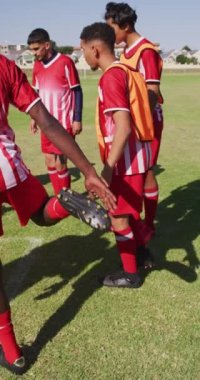 Farklı erkek futbol takımlarının saha germe hareketlerinin dikey videosu. Erkek futbol takımı, kapsayıcılık ve takım sporlarına uygunluk.