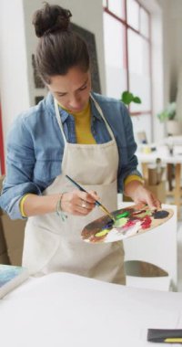 Stüdyoda çift ırklı kadın ressamın dikey videosu. Sanat, el sanatları, yaratıcılık ve yaratılış süreci kavramı.