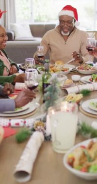 Mutlu Afro-Amerikan ailesinin Noel yemeği yediği dikey video. Noel konseptinde aileyle kaliteli zaman geçirmek.