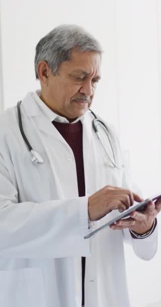 Vídeo Vertical Del Médico Varón Birracial Senior Usando Tableta Servicios — Vídeo de stock