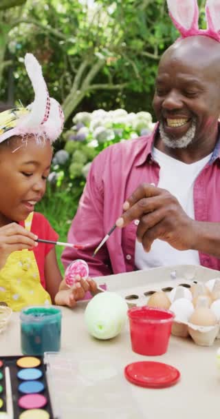 Pionowe Wideo Szczęśliwego Afrykańskiego Dziadka Wnuczki Malujących Jajka Wielkanoc Spędzanie — Wideo stockowe