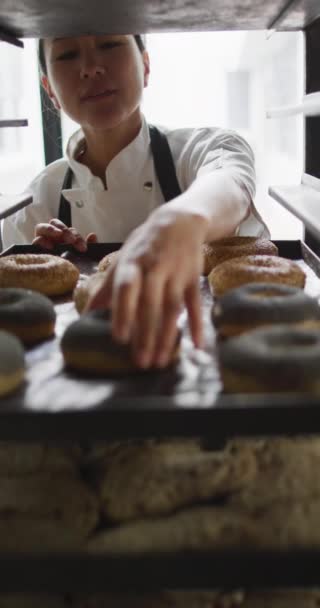 Pionowe Wideo Szczęśliwej Azjatyckiej Piekarki Przygotowującej Pączki Piekarni Globalne Przedsiębiorstwa — Wideo stockowe
