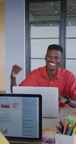 幸せなアフリカ系アメリカ人男性の垂直ビデオワークデスクでコンピュータを介して同僚と拳をぶつける 創造的なビジネスでの職場での成功を祝う身体の包容力 — ストック動画