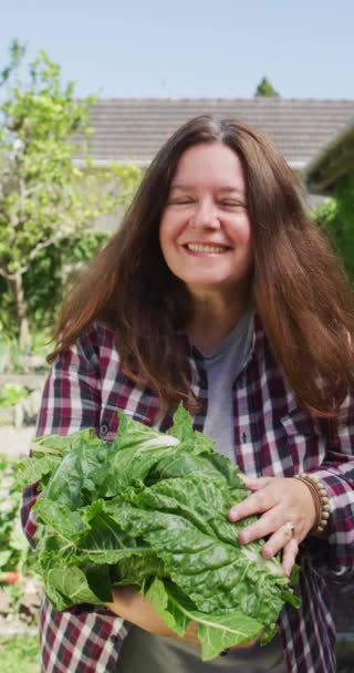 Вертикальне Відео Усміхненої Білої Жінки Сонячному Саду Несе Свіжовибрану Зелень — стокове відео