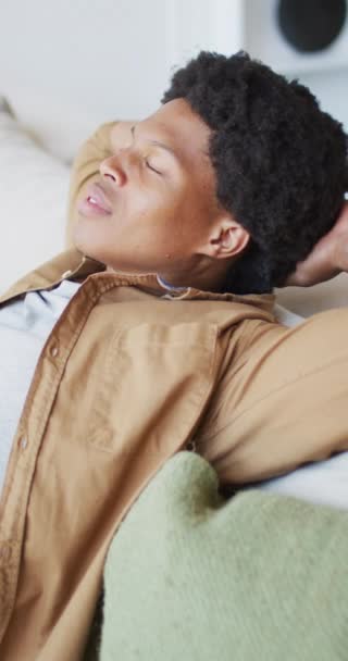 Vertikální Video Šťastného Afroameričana Relaxujícího Gauči Zavřenýma Očima Slunném Pokoji — Stock video