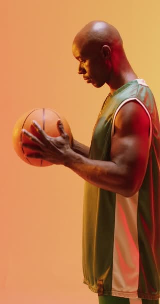 Вертикальне Відео Африканського Чоловічого Баскетболу Тримає Помаранчевому Тлі Спорт Конкуренція — стокове відео