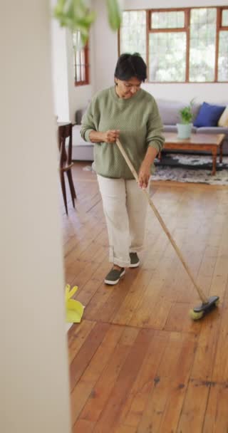 リビングルームでのシニア助産師の掃除床の垂直ビデオ 家での健康的で活発な退職は — ストック動画