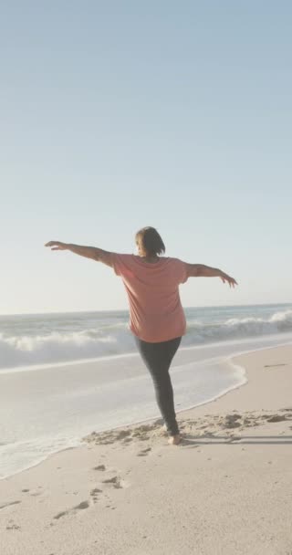 一个快乐的老年非洲裔美国妇女的垂直视频 她在海滩上张开双臂 在海滨度假时消闲 — 图库视频影像