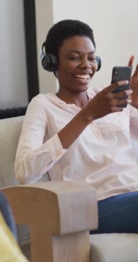 Kulaklık takan mutlu Afro-Amerikan kadının akıllı telefonuyla video konuşması. ev hayatı, evde boş vakitlerin tadını çıkarmak..