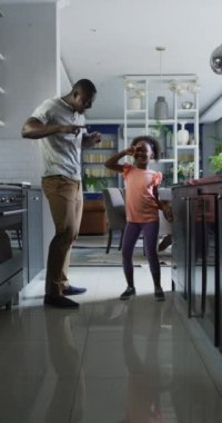 Vertical video of african american father and daughter dancing. Enjoying quality family time together at home.