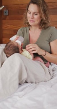 Yeni doğmuş bebekle oynayan mutlu beyaz bir annenin dikey videosu. annelik, ebeveyn sevgisi ve yeni doğan bebek konseptiyle ilgilenmek dijital olarak üretilmiş video.