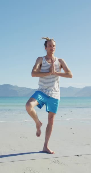 Pionowe Nagranie Zrelaksowanego Białego Mężczyzny Dredami Ćwiczącego Jogę Plaży Zdrowy — Wideo stockowe