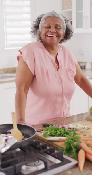 キッチンでの幸せなシニアアフリカ系アメリカ人女性の料理の垂直ビデオ 引退と家のコンセプトでの時間を過ごす — ストック動画