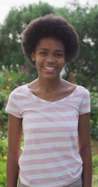 庭でアフリカ系アメリカ人の10代の少女の笑顔の垂直ビデオ肖像画 家庭での身体的包容力国内生活と質の高い時間 — ストック動画