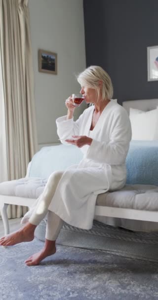 Vertical Video Happy Senior Caucasian Woman Sitting Bed Bedroom Drinking — Stock Video